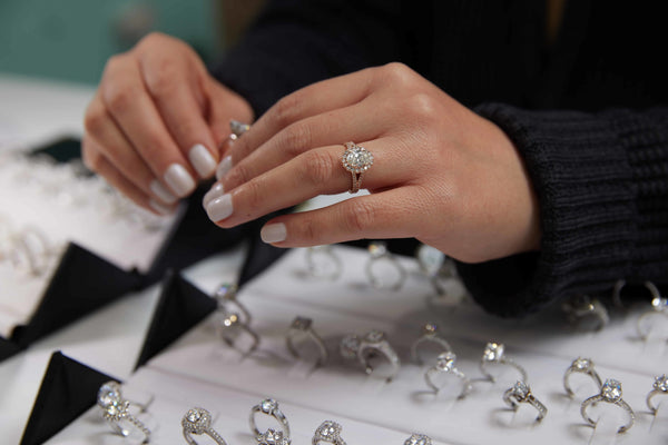 A hand wearing a moissanite engagement ring while shopping for other engagement rings