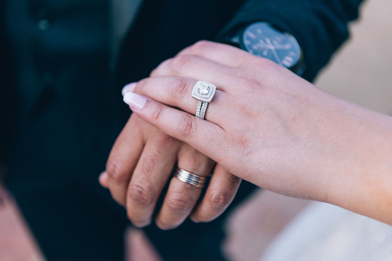A woman wearing her moissanite engagement ring while holding her husband's hand.